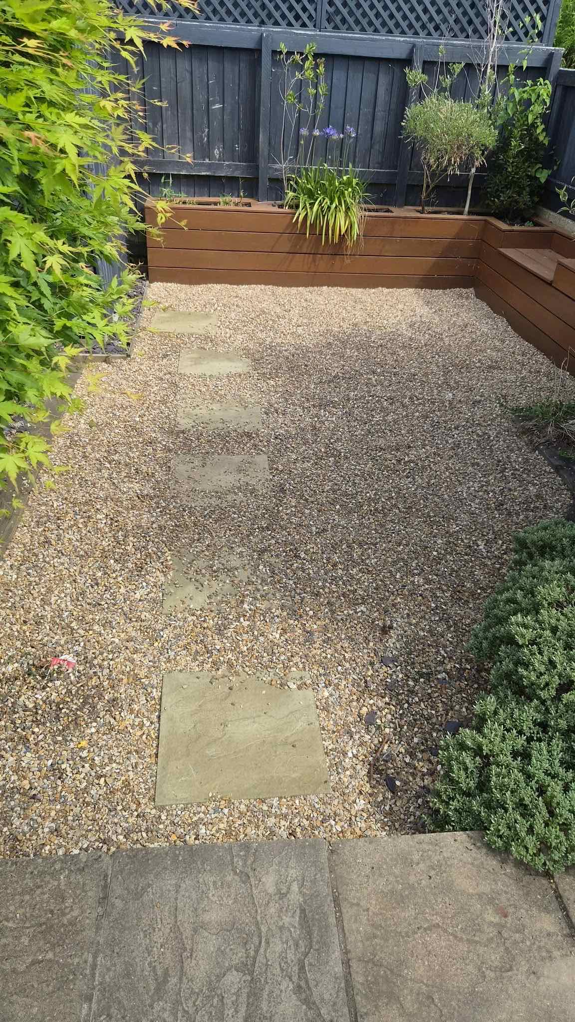 Tidied gravel garden with raised timber bed and stepping stones